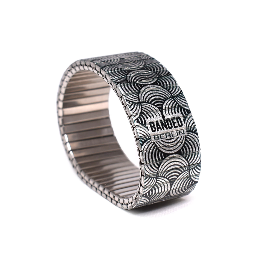 This metallic black and white beauty has everything you need for a healthy self diagnosis. A mainstay in the black and whites collection, we love the fluidity of the weaving lines in and around the wrist. Now available in our signature 23mm king size width.  Made in Berlin, Germany © 2020, banded berlin.